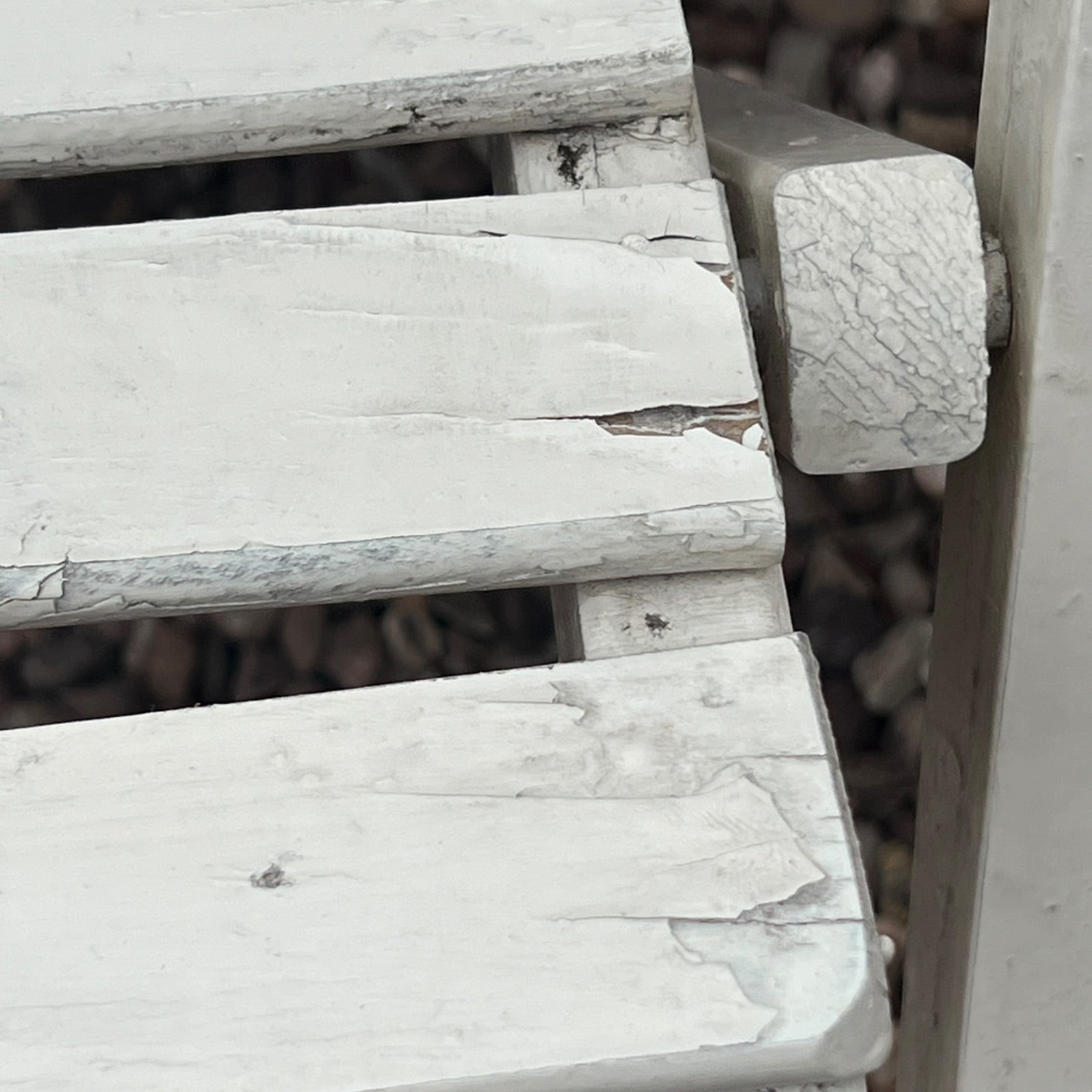 A close-up view of a painted wooden slatted garden chair set amidst a lush garden backdrop.