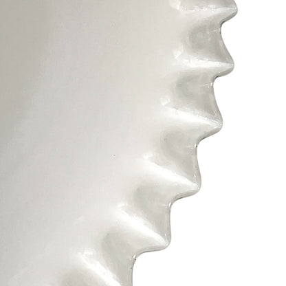 Close-up of a white glass lampshade with wavy design on a white background
