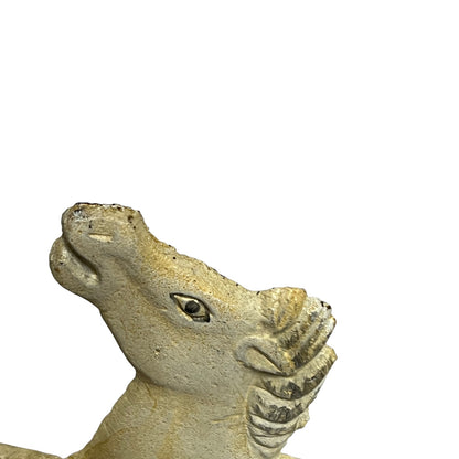 Close-up of a textured stone or concrete horse head sculpture on a plain white background.