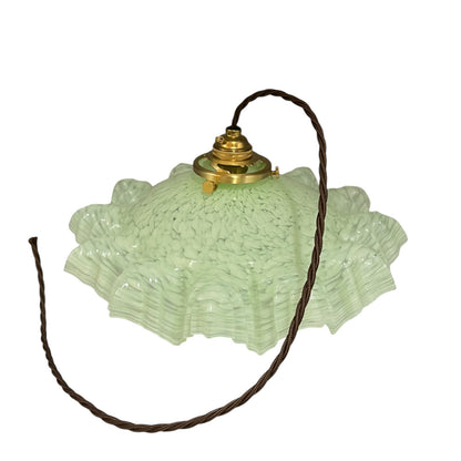 A vintage-style light fixture featuring a textured, ruffled light green glass shade with a brass metal top and a dark brown hanging cord, shown against a plain white background.