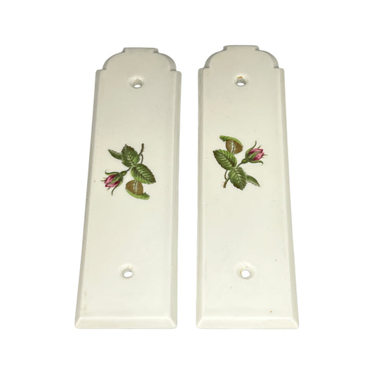 Pair of white door push plates with floral designs on a white background