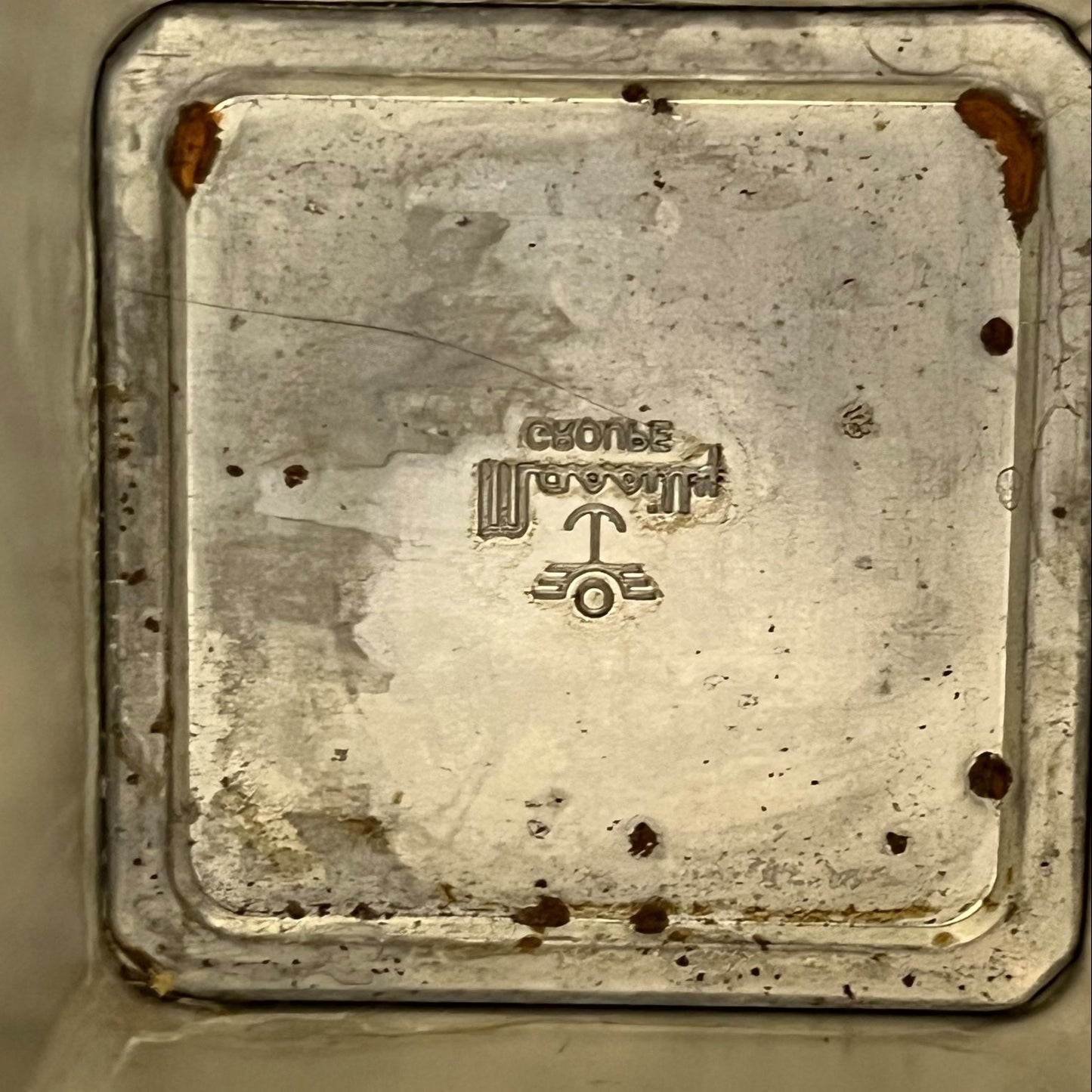 Rust-covered metal plate with engraved text and symbols