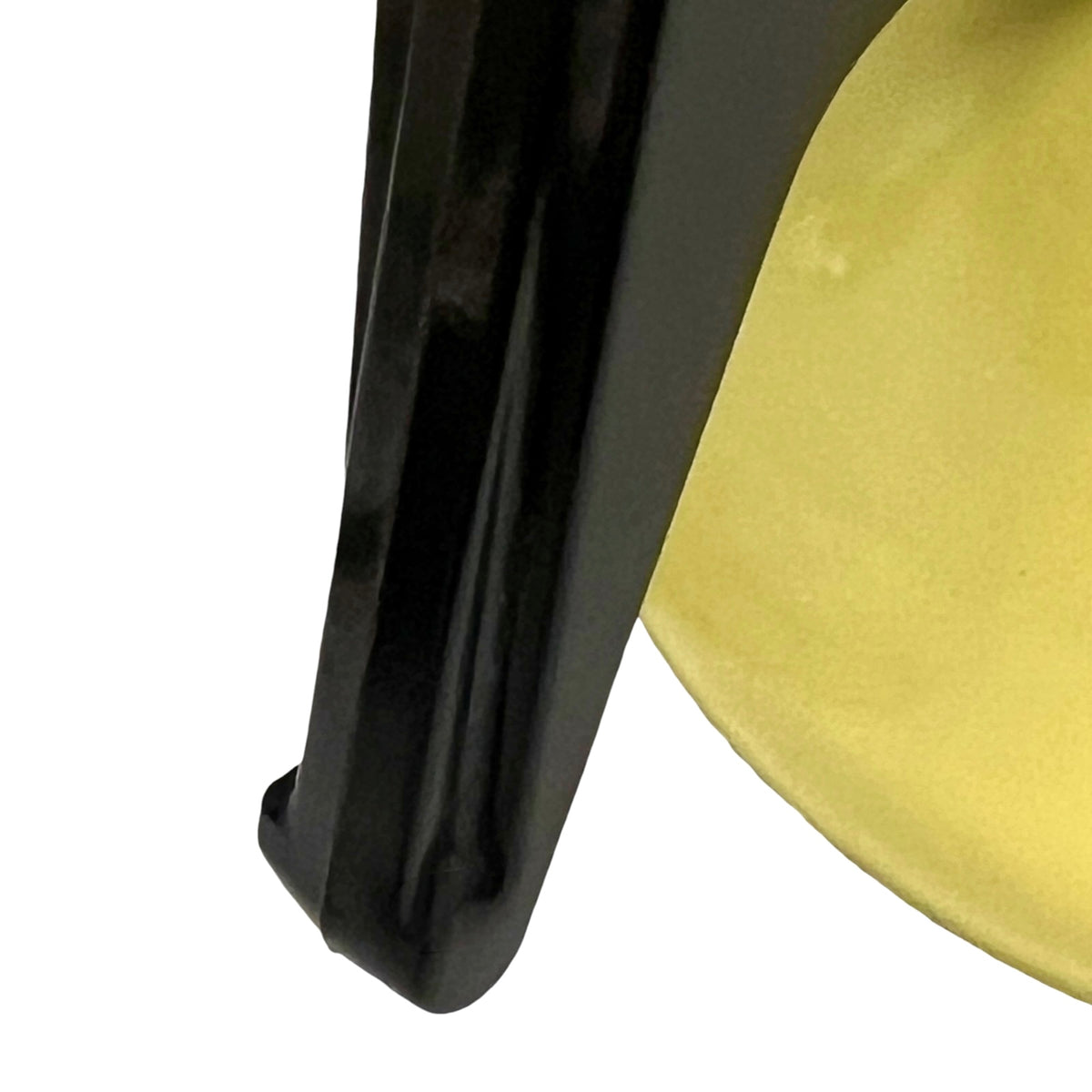 Close-up of a glossy black curved object next to a yellow circular surface on a white background.