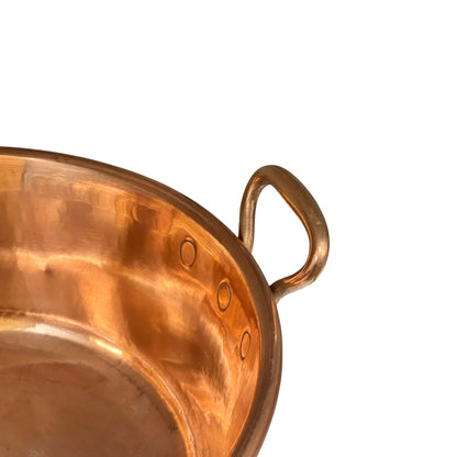 Close-up of a hammered copper pot showing the interior, rim, and a D-shaped side handle against a plain white background.