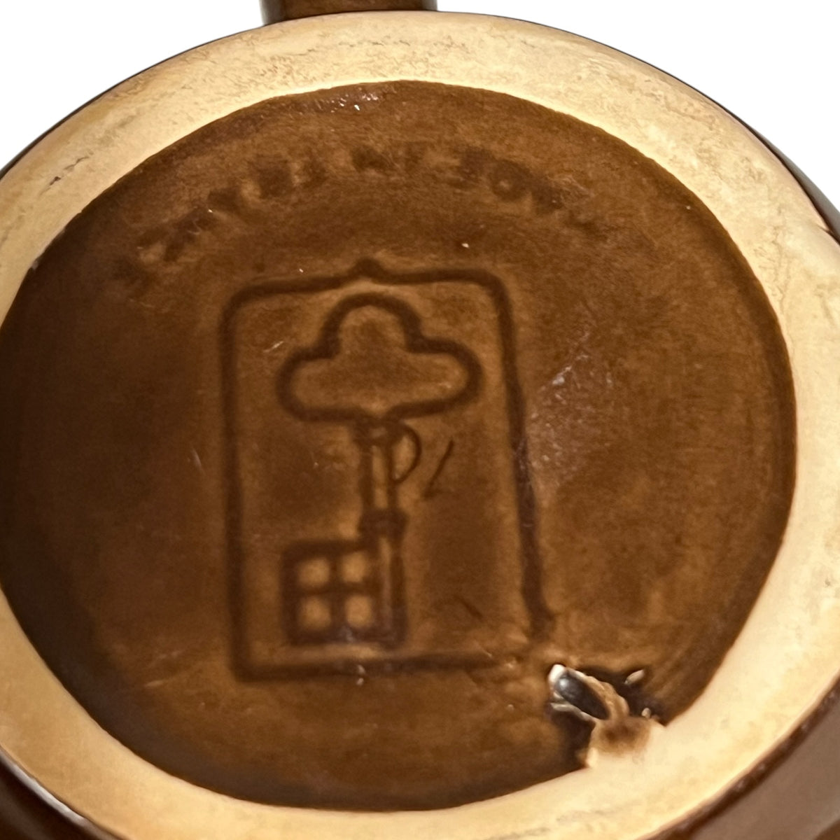 Close up detail view of Emile henry makers stamp in the shape of a key shown on an escargot dish on a white background 