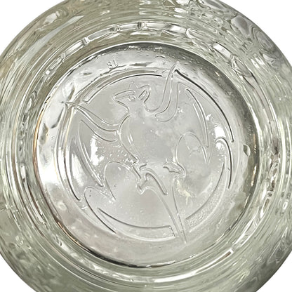 A close-up of a clear glass bowl or dish with a raised embossed bat design in the center and a textured, ribbed rim.