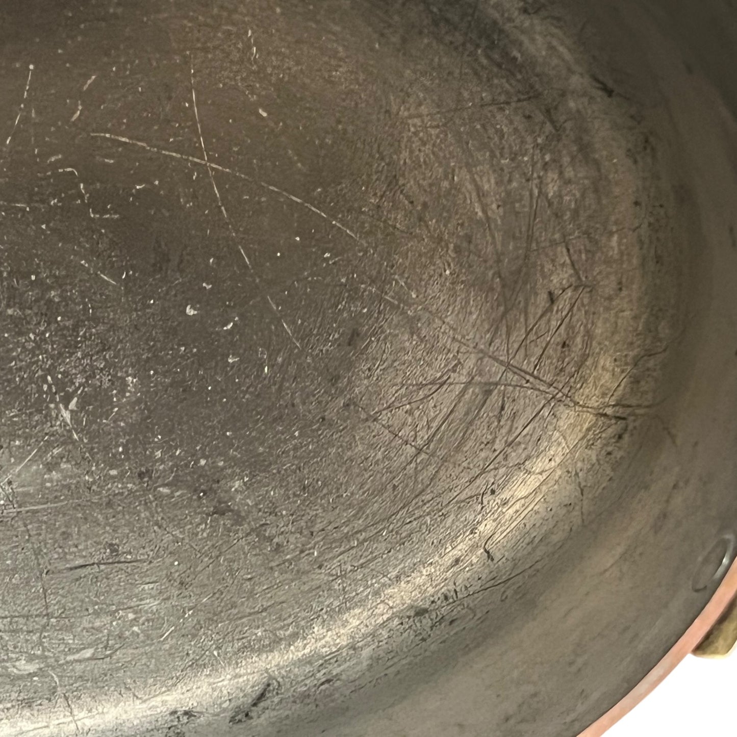 Close up of the inside of a French copper pan with tin lining on a white background