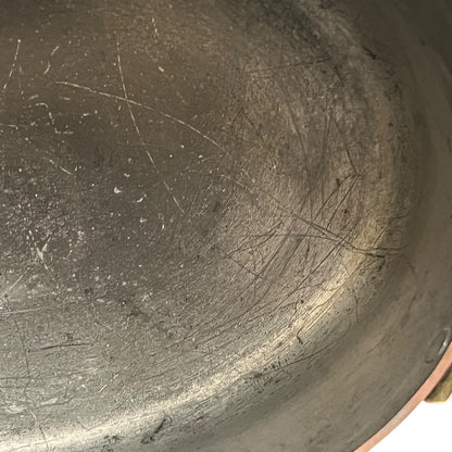 Close up of the inside of a French copper pan with tin lining on a white background