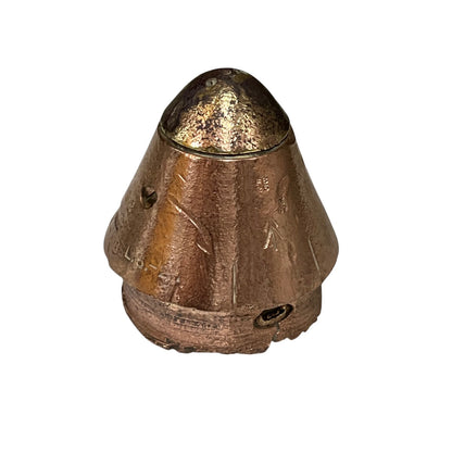 A small metallic bronze-colored object with a conical top and textured, worn surface, photographed against a plain white background.