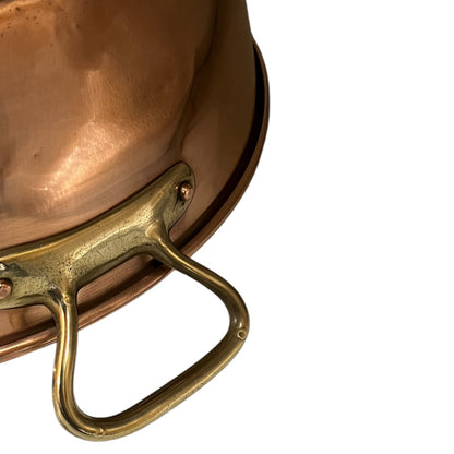 Close-up of a copper up cycled sink with brass handles on a white background.