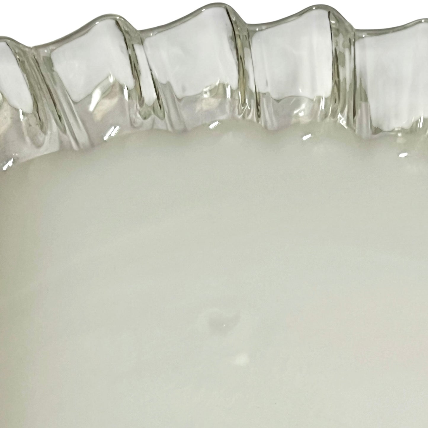 Close-up of a milk glass lampshade with a wavy, scalloped rim and a smooth, opaque white interior.