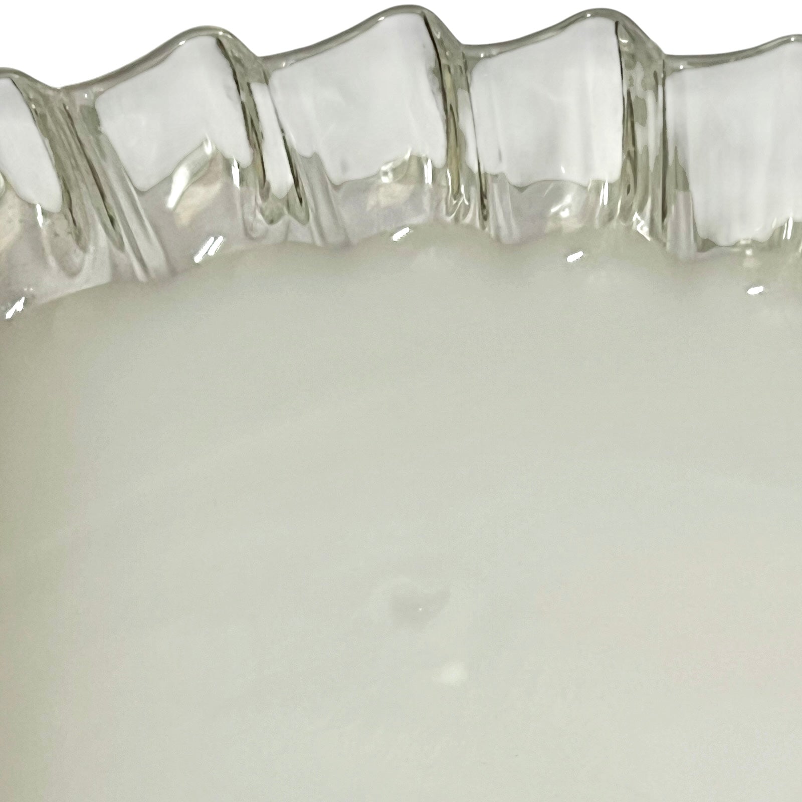 Close-up of a milk glass lampshade with a wavy, scalloped rim and a smooth, opaque white interior.