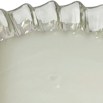 Close-up of a milk glass lampshade with a wavy, scalloped rim and a smooth, opaque white interior.