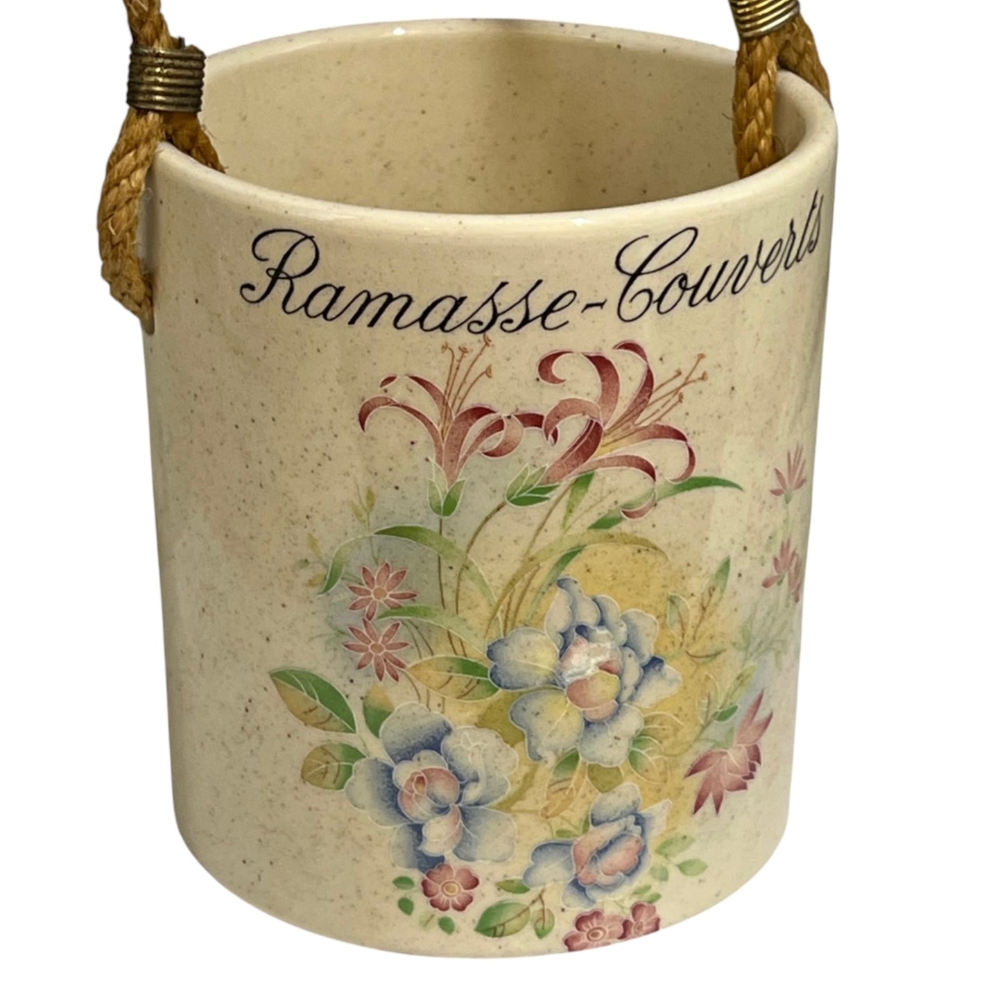 A vintage-style ceramic bucket with a speckled cream-beige finish, featuring a floral illustration and the cursive text 'Ramasse-Couverts' on the front. It has two braided rope handles with brass hardware, shown against a plain white background.