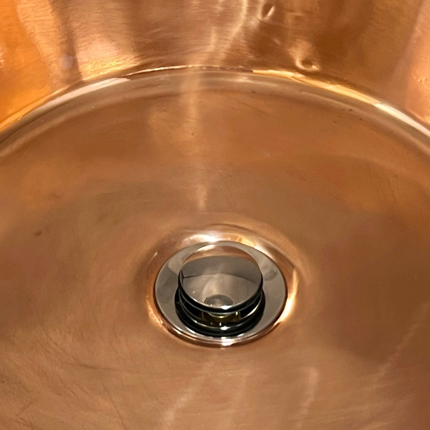 Close-up of a copper sink with a drain