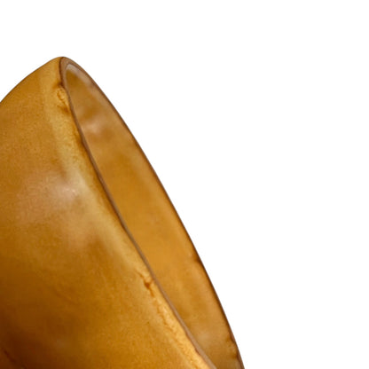 A close-up detail shot of a smooth, curved amber-brown storage jar, on a solid white background.