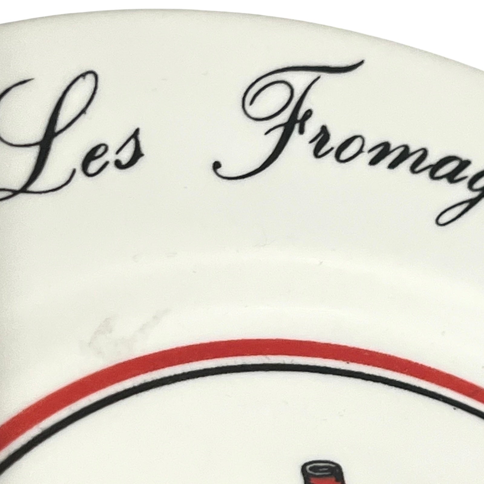 Close-up of a ceramic plate with 'Les Fromages' text and red and black design.