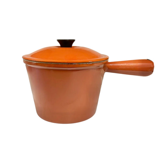 Rust coloured enamelled cast iron saucepan with lid on a white background