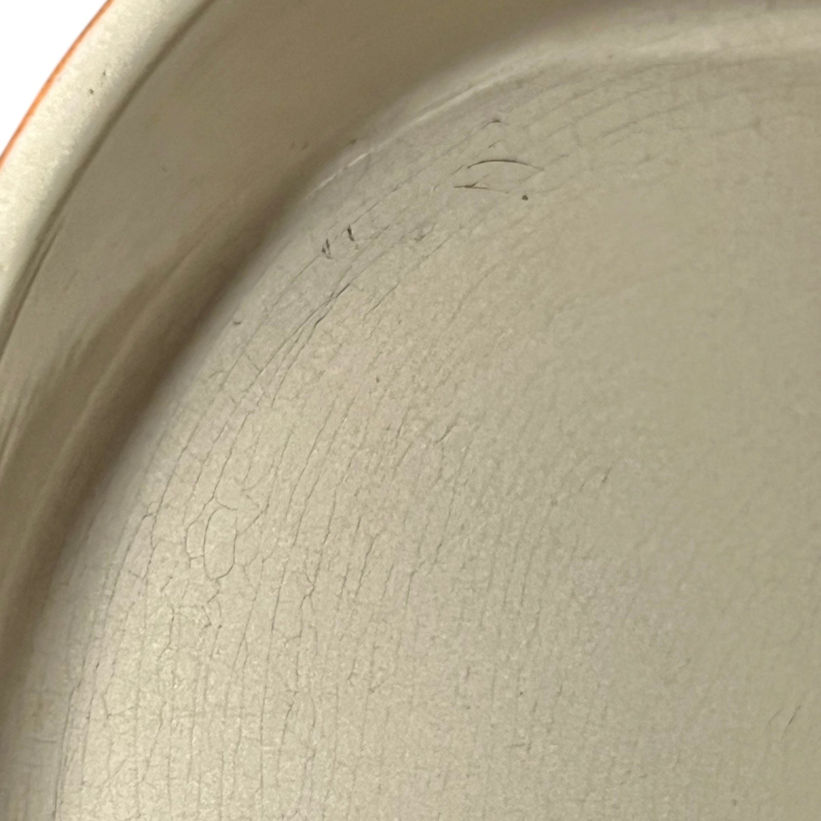 Close up of Le Creuset dish with beige interior on a white background