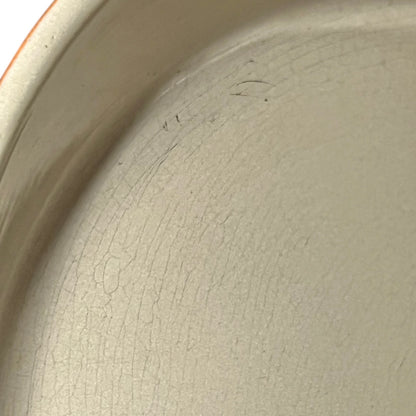 Close up of Le Creuset dish with beige interior on a white background
