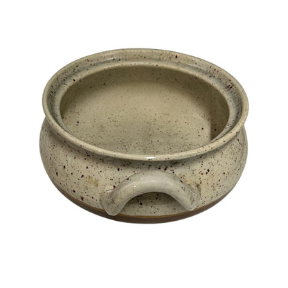 Close up of a speckled ceramic container on a white background