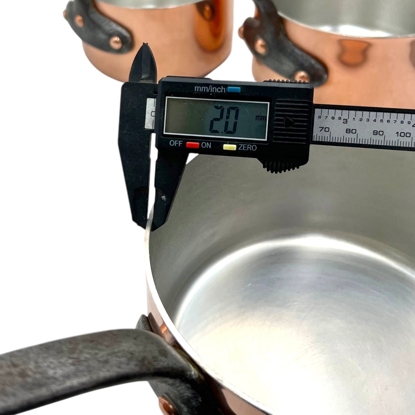 Digital caliper measuring the depth of a metallic pot.