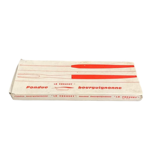 Box of Le Creuset fondue sticks with red handles on a white background