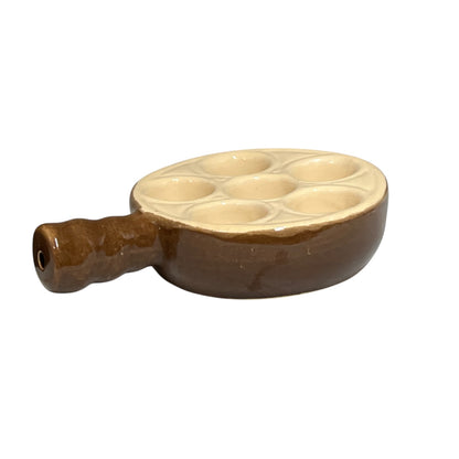 A brown ceramic escargot plate with a handle and a cream-colored interior chamber featuring six circular indentations, shown on a plain white background.