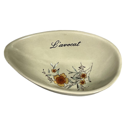 Beige ceramic dish with floral design and 'L'avocat' text on a white background