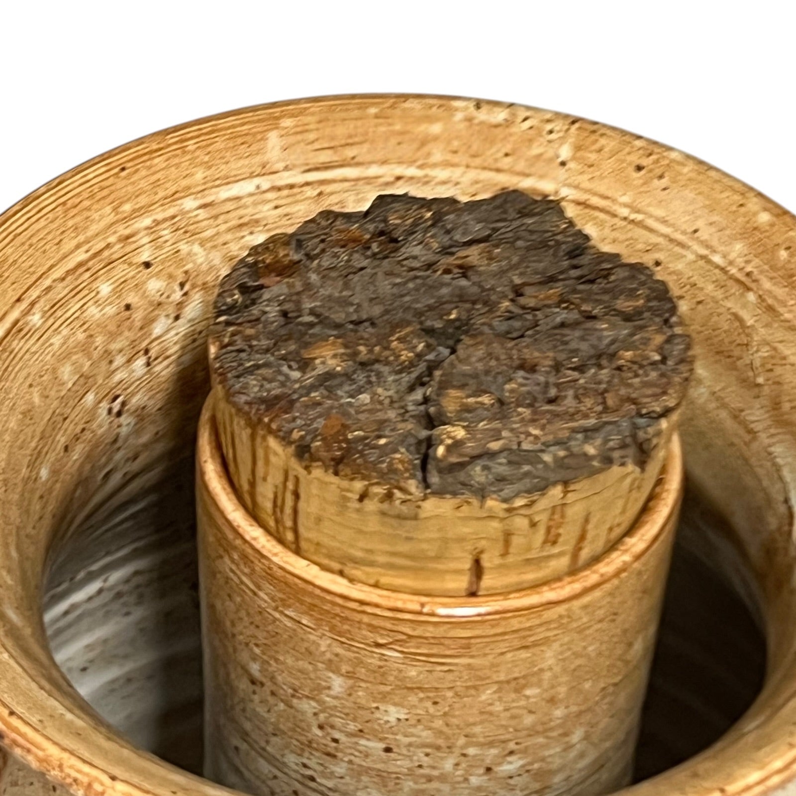 Close-up of a cork stopper in a ceramic container on a white background