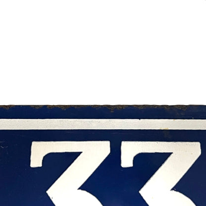 Close-up of a dark blue sign or plaque with a white horizontal stripe and large white numerals '133' visible at the bottom.