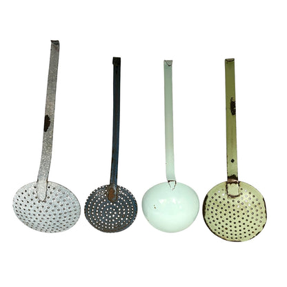 Four vintage metal kitchen ladles with perforated strainers are lined up horizontally against a plain white background. The ladles have long handles and round bowls, showing different colors and finishes: silver, dark gray, pale mint green, and olive green.