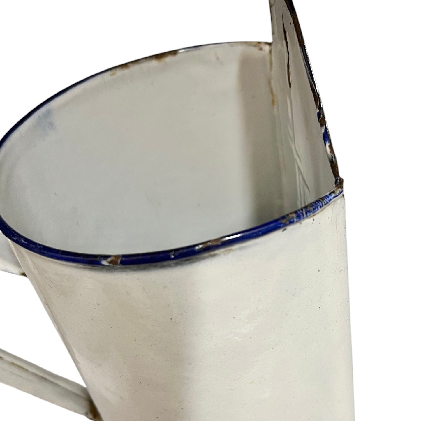 A close-up of a vintage white enamel pot with a blue rim and a distressed, weathered finish.