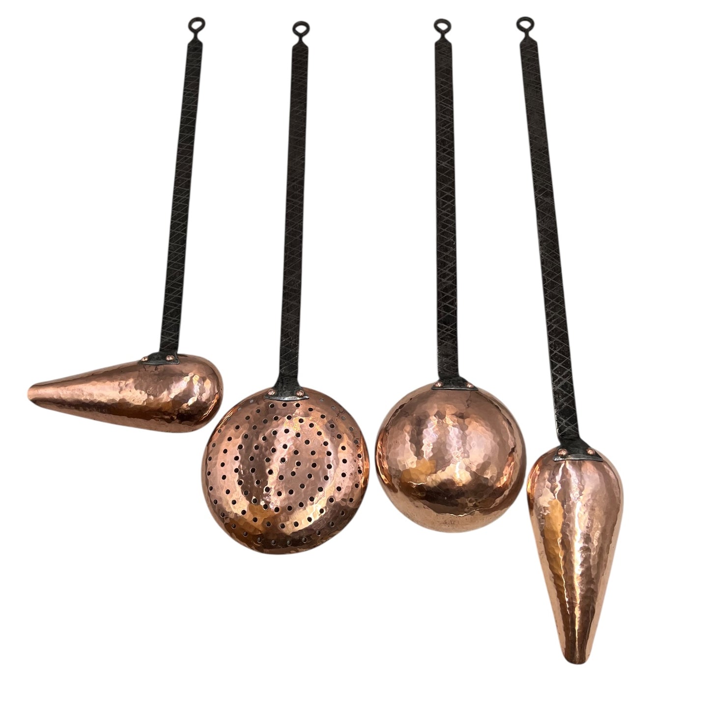 Set of four copper kitchen utensils with black handles on a white background