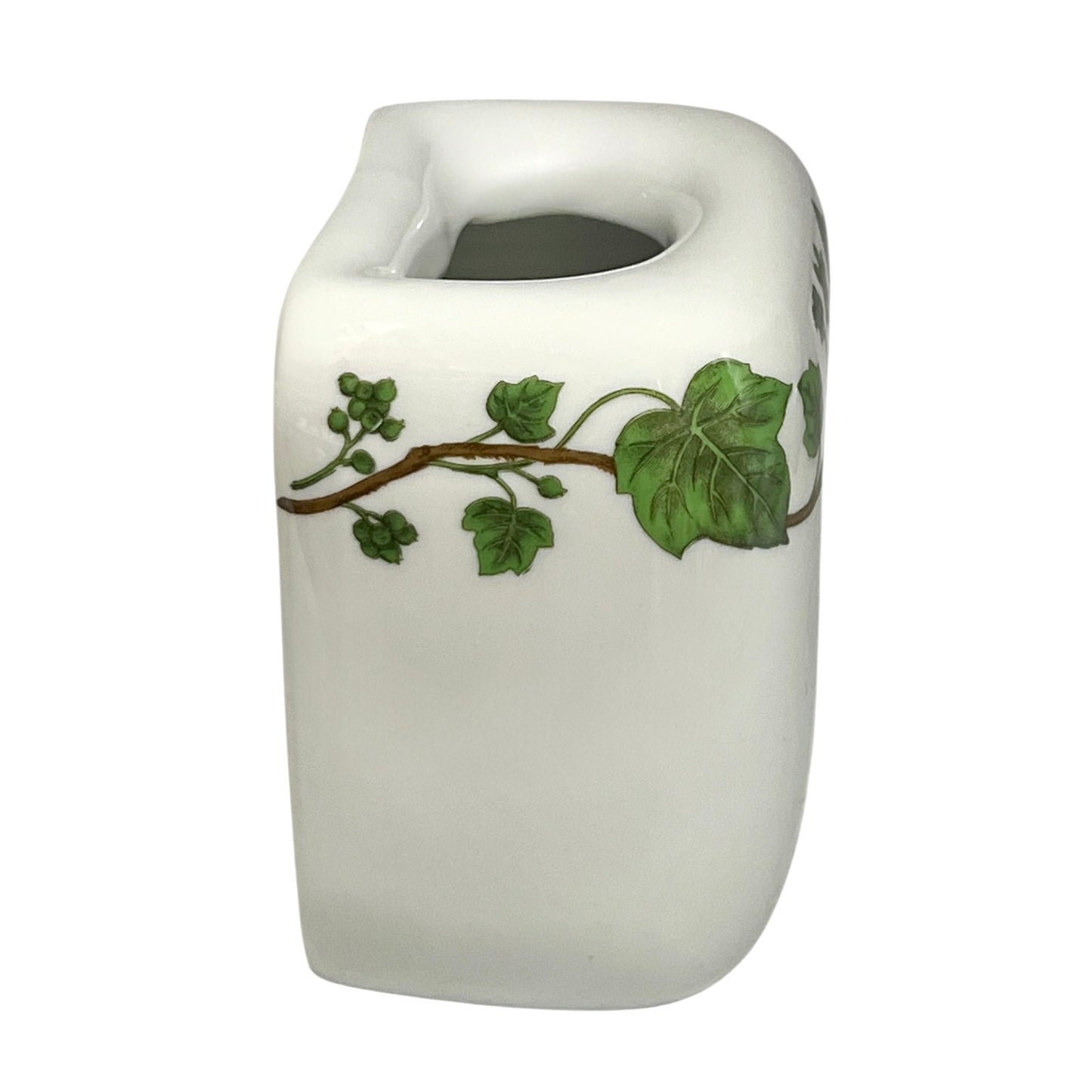 White ceramic toothbrush pot with green leaf design on a white background