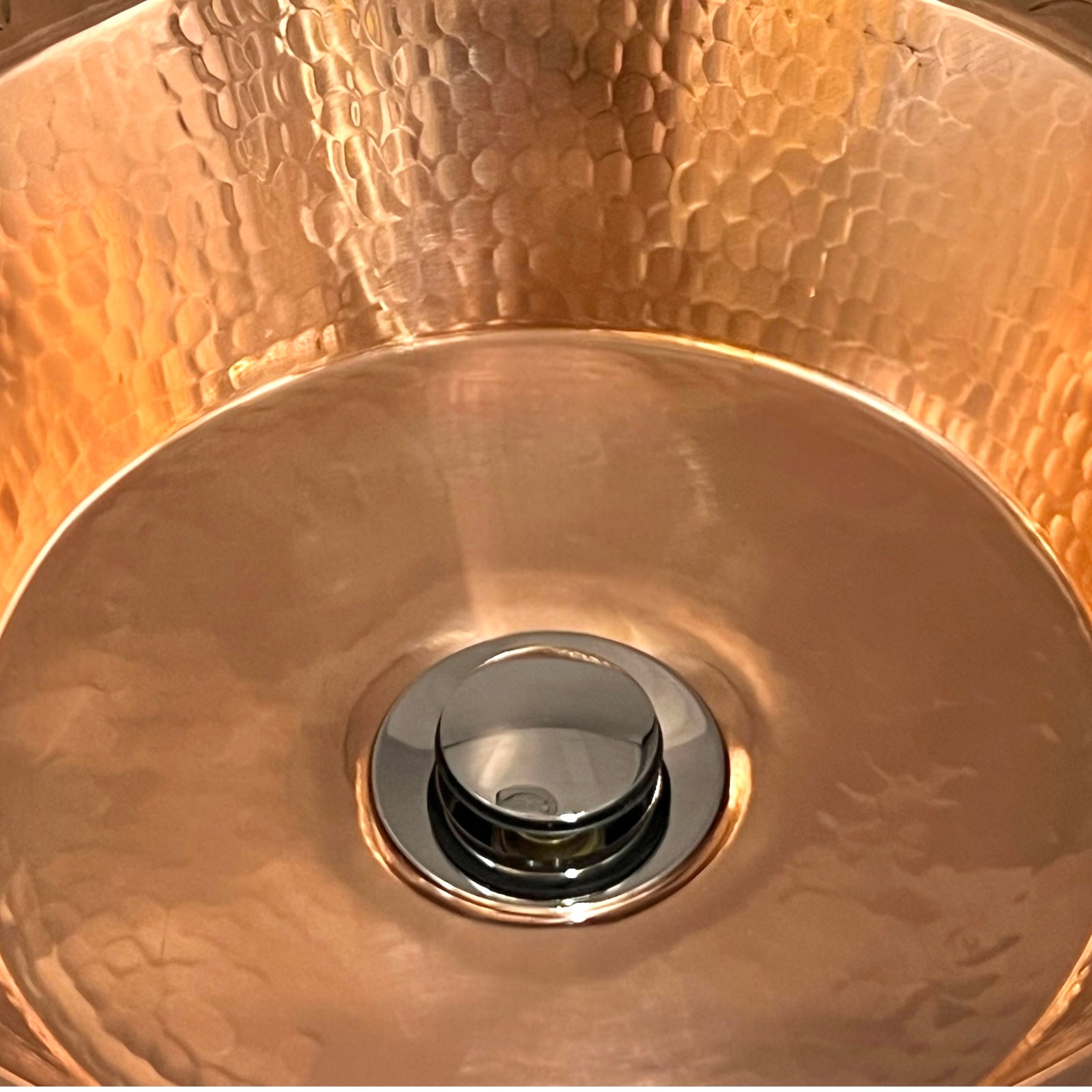 Close-up of a copper sink with a shiny drain