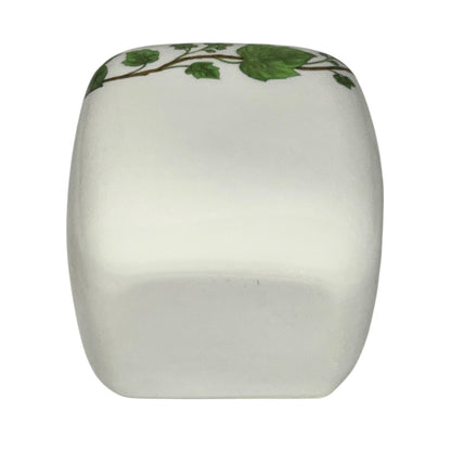 White ceramic toothbrush pot with green leaf design on a white background