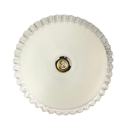 close up of brass ceiling light fixture with white glass shade on a white background