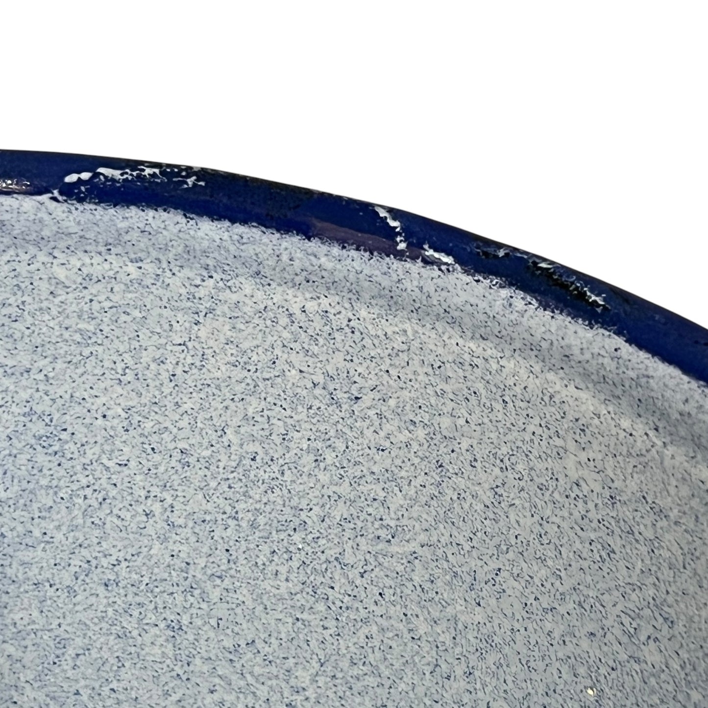 A close-up of a speckled blue textured surface with a dark navy blue curved edge against a white background.
