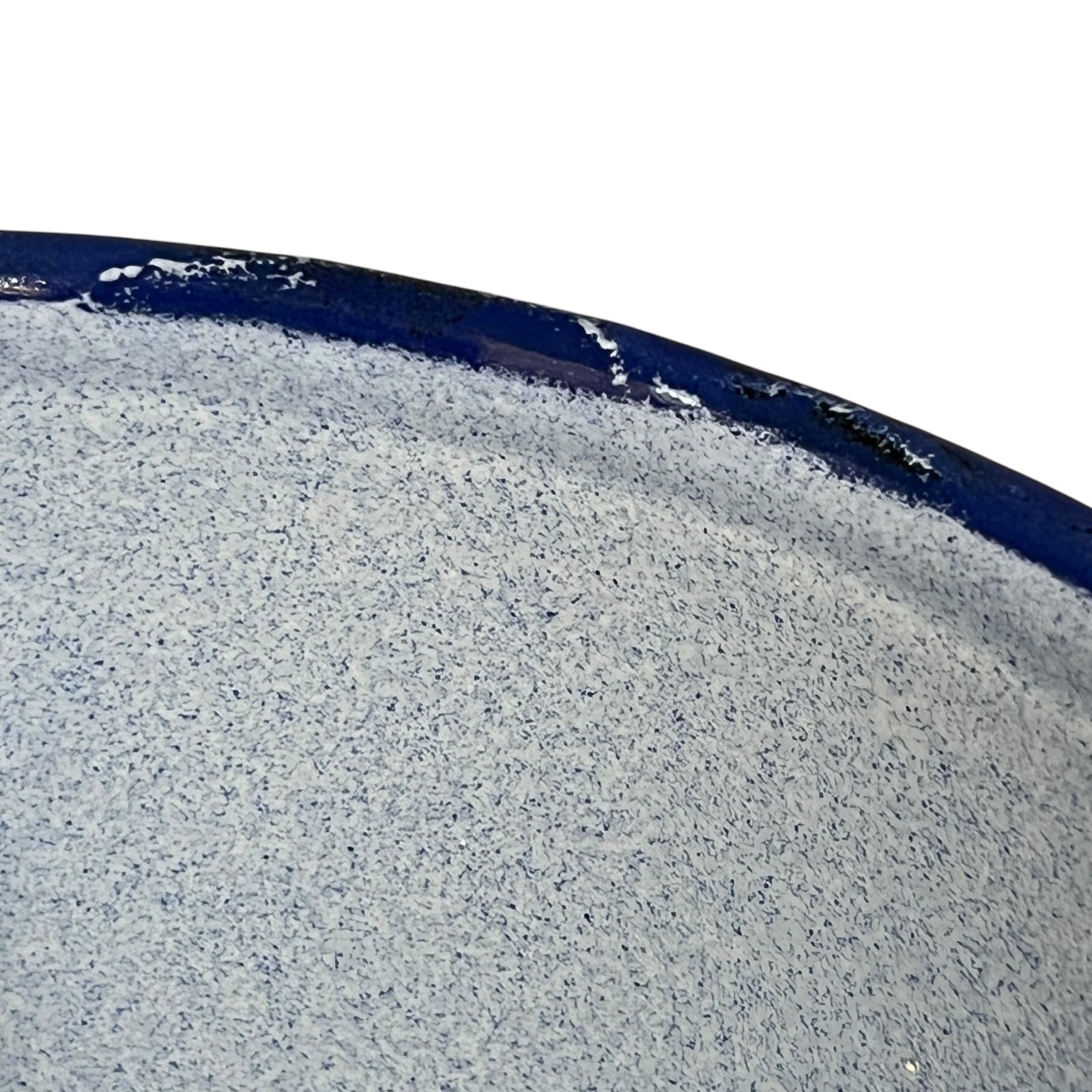 A close-up of a speckled blue textured surface with a dark navy blue curved edge against a white background.