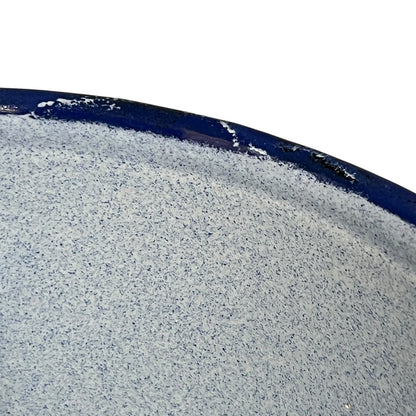 A close-up of a speckled blue textured surface with a dark navy blue curved edge against a white background.