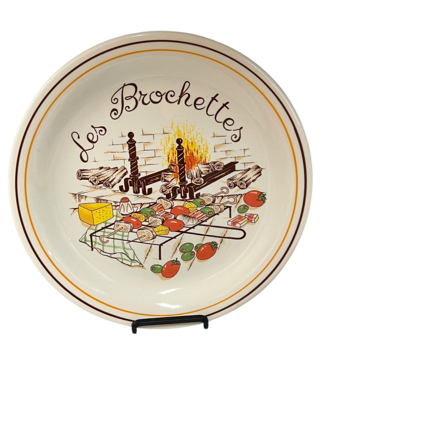 Decorative plate with a grill scene and 'Les Brochettes' text on a white background