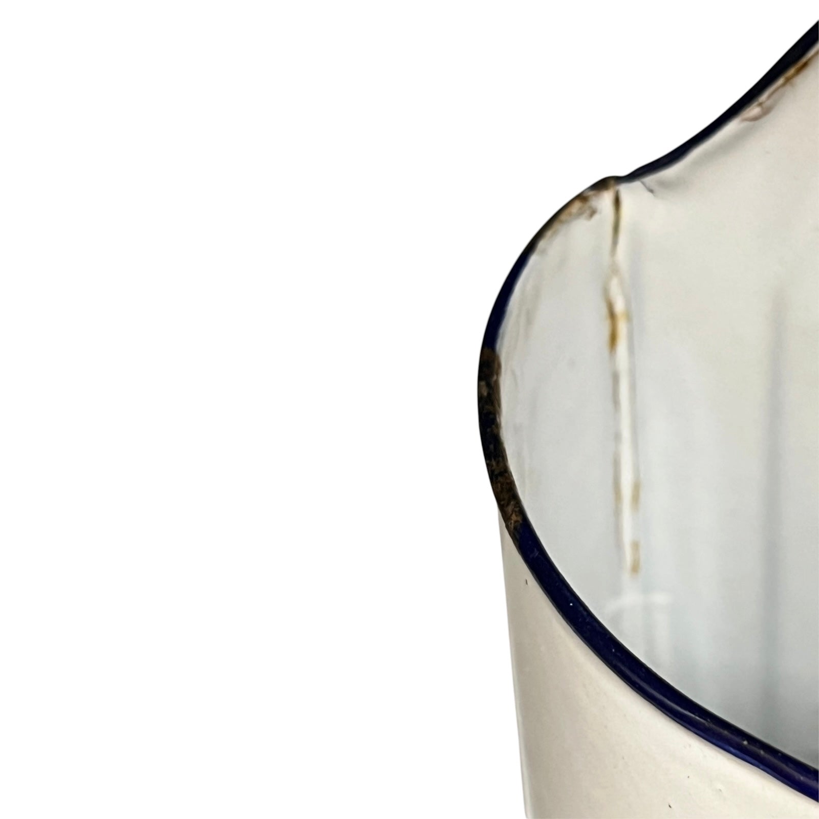 Close-up of a white enamel jug with a dark blue rim, showing a vertical stain or chipped area on the edge against a white background.