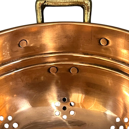 Close up of a copper colander with on a white background