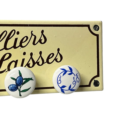 A dog lead hook plaque displayed on a cream-coloured enamel sign that reads 'Colliers Laisses'.