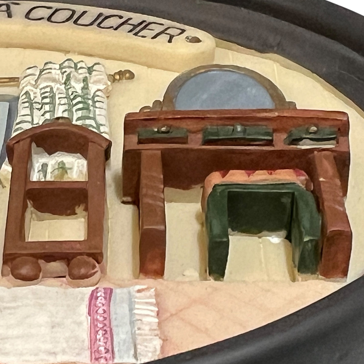 A close-up of a miniature dollhouse furniture set sign , featuring a brown wooden vanity desk with a mirror, a matching side cabinet, and a green upholstered chair on a beige base.