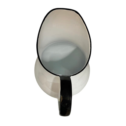White pitcher with black handle and rim on a white background