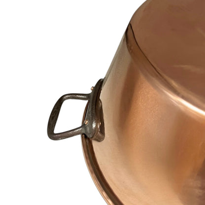 Close up of French copper bowl upcycled into a copper sink with cast iron handles on a white background