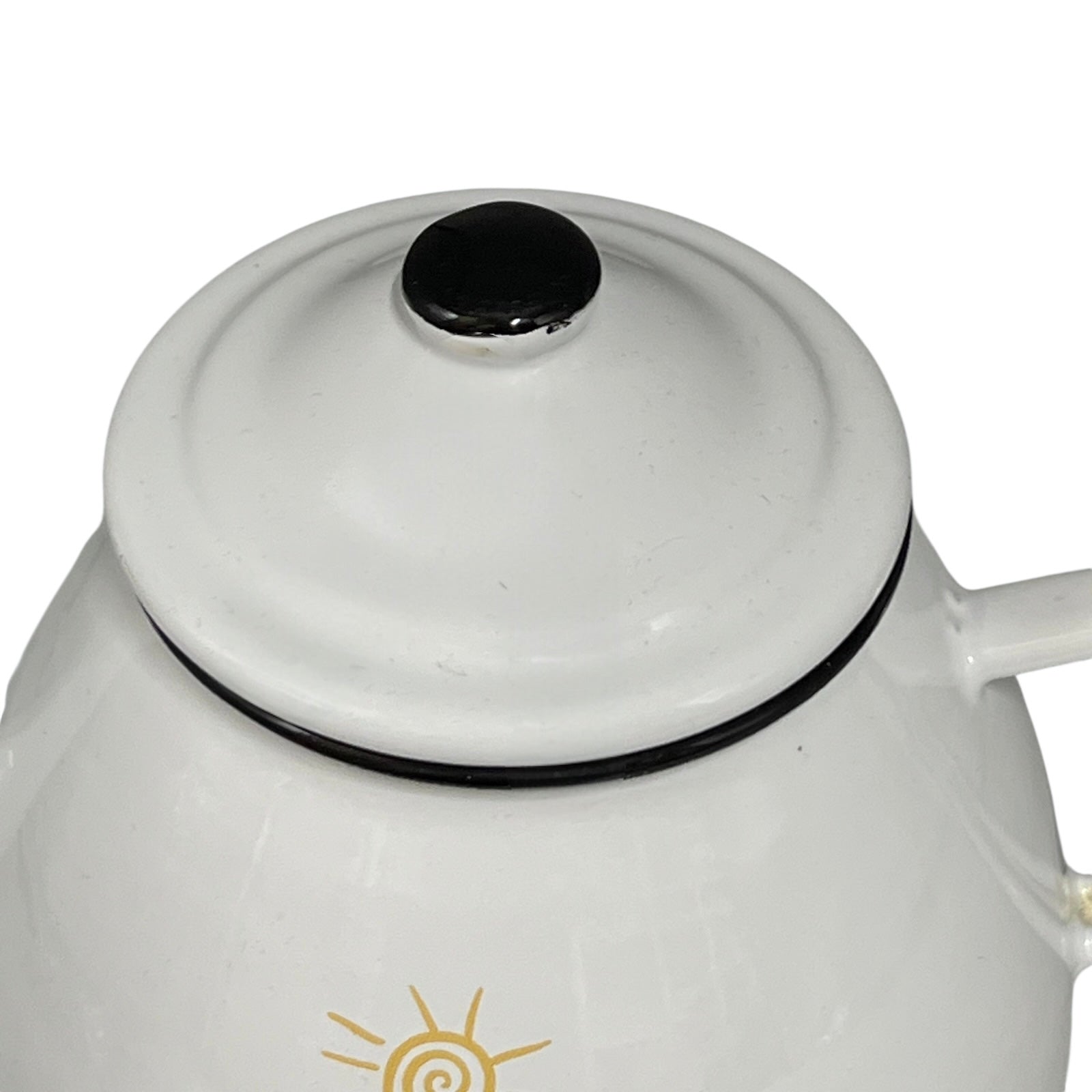 White enamel teapot with black lid and cow design on a white background