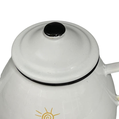 White enamel teapot with black lid and cow design on a white background